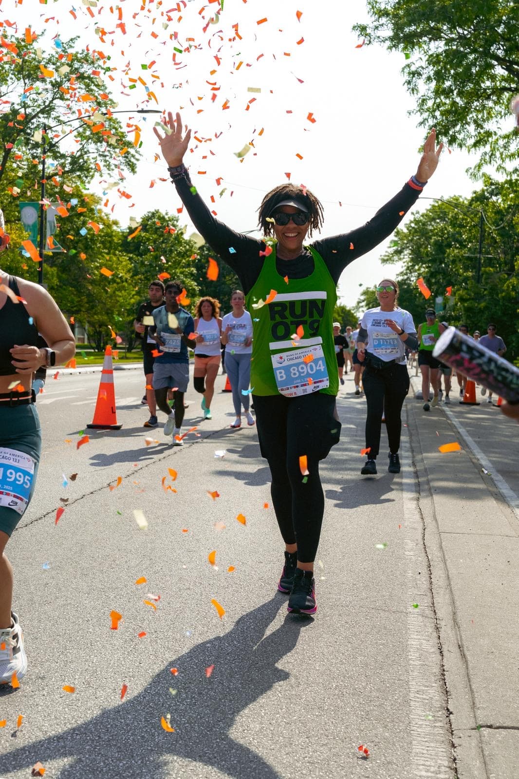 Crew member in the RUN OT9 singlet, arms up through the confetti at the Chicago 13.1
